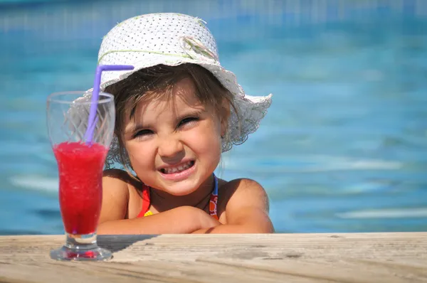 Klein meisje in het zwembad met cocktail — Stockfoto