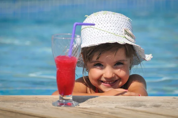 Klein meisje in het zwembad met cocktail — Stockfoto