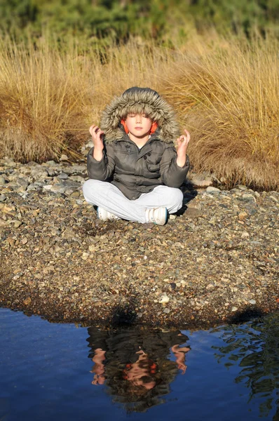 银行的山区河流上的冥想的男孩 — 图库照片