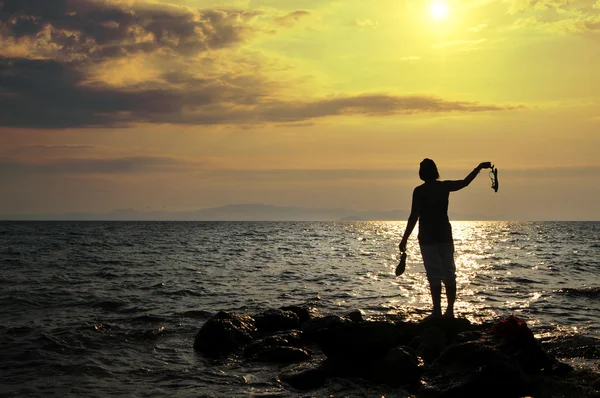 Νεαρή γυναίκα στέκεται σε βράχο στη θάλασσα και ψάχνει κάπου — Φωτογραφία Αρχείου