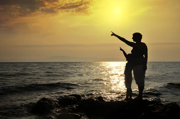 Young woman and boy standing on rock in sea and looking to somewhere — Stock Photo, Image