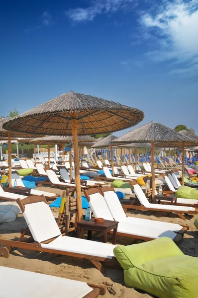 Sandy beach with wooden parasols and deck chairs — Stock Photo, Image