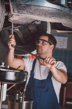 Araba tamircisi oto tamir servisinde çalışıyor.