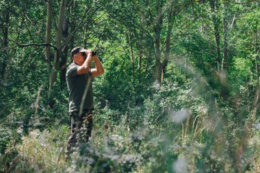 Dürbünü doğanın arka planına karşı olan adam. Kuşların gözlemlenmesi.