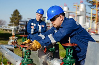 Petrol işçisi petrol platformunda vanayı çeviriyor.
