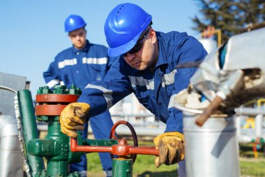 Petrol işçisi petrol platformunda vanayı çeviriyor.