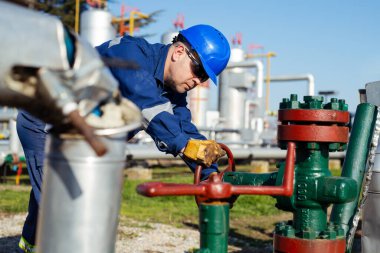 Petrol işçisi petrol platformunda vanayı çeviriyor.