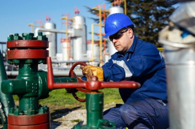 Petrol işçisi petrol platformunda vanayı çeviriyor.
