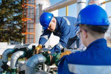 Petrol işçisi petrol platformunda vanayı çeviriyor.
