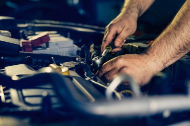 Tamirci tamirhanede araba motoru üzerinde çalışıyor..