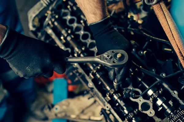 Tamirci tamirhanedeki araba motoru tamir ediyor.