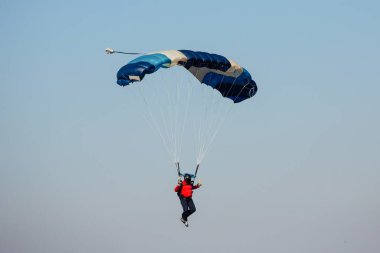 Gökyüzünde paraşüt. Paraşütçü mavi gökyüzünde paraşütle atlıyor..