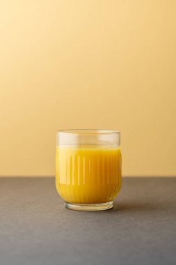 Portakal suyu, parlak ışıkta, renkli bir arkaplanda izole edilmiş. Bir bardak portakallı meyve suyu. Yaz tropik kokteyli.