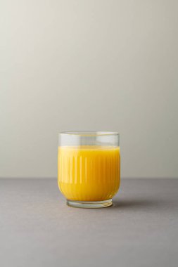 Portakal suyu, parlak ışıkta, renkli bir arkaplanda izole edilmiş. Bir bardak portakallı meyve suyu. Yaz tropik kokteyli.