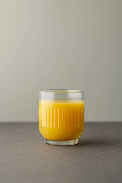Portakal suyu, parlak ışıkta, renkli bir arkaplanda izole edilmiş. Bir bardak portakallı meyve suyu. Yaz tropik kokteyli.