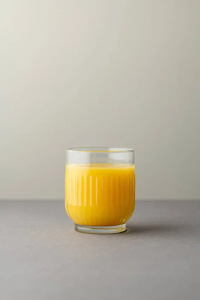 Portakal suyu, parlak ışıkta, renkli bir arkaplanda izole edilmiş. Bir bardak portakallı meyve suyu. Yaz tropik kokteyli.