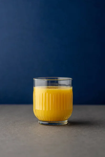 Portakal suyu, parlak ışıkta, renkli bir arkaplanda izole edilmiş. Bir bardak portakallı meyve suyu. Yaz tropik kokteyli.
