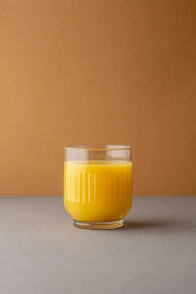 Portakal suyu, parlak ışıkta, renkli bir arkaplanda izole edilmiş. Bir bardak portakallı meyve suyu. Yaz tropik kokteyli.