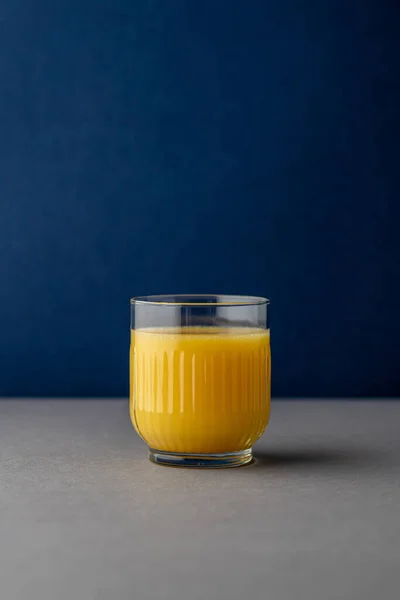 Portakal suyu, parlak ışıkta, renkli bir arkaplanda izole edilmiş. Bir bardak portakallı meyve suyu. Yaz tropik kokteyli.