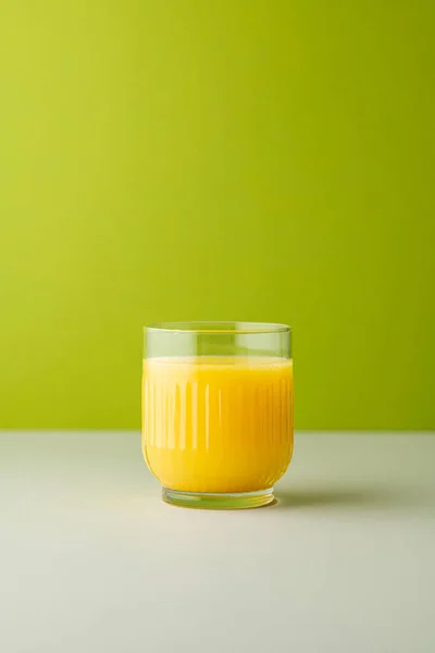 Portakal suyu, parlak ışıkta, renkli bir arkaplanda izole edilmiş. Bir bardak portakallı meyve suyu. Yaz tropik kokteyli.