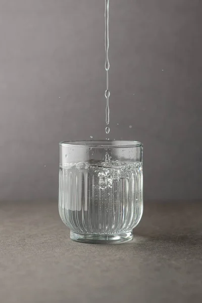 Kaynak suyu gri bir arka plan ile cam