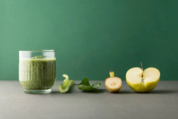 Lezzetli bir bardak detoks suyu (smoothie) ve renk arkaplanındaki malzemelerle kompozisyon