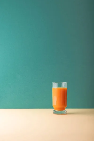 Minimalist kompozisyon ve bir bardak taze havuç suyu.