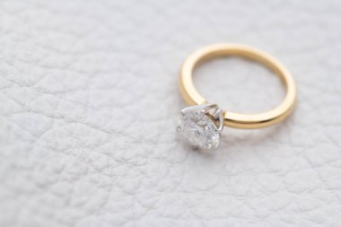 Gold Engagement Diamond Ring on White Leather Background