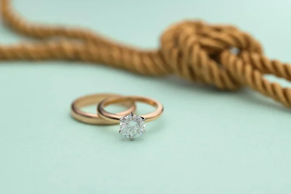 Gold Engagement Diamond Ring on Tiffany Color Background With Golden Rope