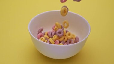 Bowl with multi-colored cornflakes slowmotion