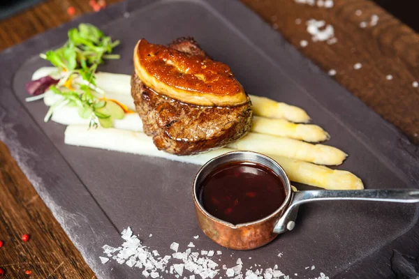 Tournedos Rossini. Foie gras, Black Angus beef tenderloin, white asparagus, red wine sauce. Delicious healthy traditional food closeup served for lunch in modern gourmet cuisine restaurant