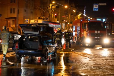 İtfaiyeciler, yol kenarında yanan bir arabayı söndürüyorlar. İtfaiyeci yol kenarındaki kazadan sonra arabadaki yangını suyla söndürüyor. Kharkov, Ukrayna, 22.10.2021