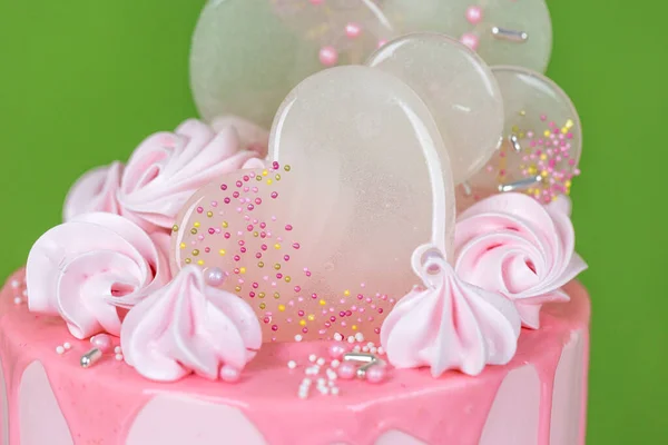 メレンゲとイソマルトロリポップで装飾されたチョコレートチップガージとピンクのクリームチーズケーキ 緑の背景に美しいおいしい誕生日ケーキ メニューやお菓子カタログの写真 — ストック写真