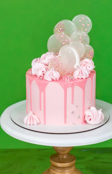 メレンゲとイソマルトロリポップで装飾されたチョコレートチップガージとピンクのクリームチーズケーキ 緑の背景に美しいおいしい誕生日ケーキ メニューやお菓子カタログの写真 — ストック写真