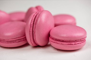 Makarnalar beyaz ahşap arka planda yakınlaşır. Tatlı ve renkli pembe Fransız badem kurabiyeleri. Evde yemek pişirmek.. 