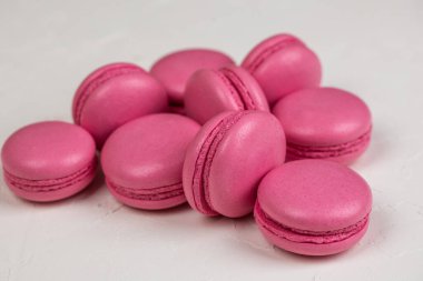 Makarnalar beyaz ahşap arka planda yakınlaşır. Tatlı ve renkli pembe Fransız badem kurabiyeleri. Evde yemek pişirmek.. 