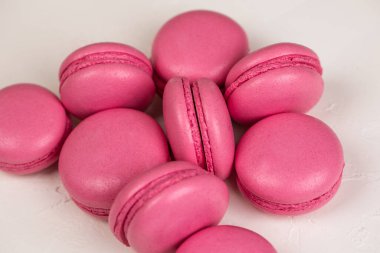 Makarnalar beyaz ahşap arka planda yakınlaşır. Tatlı ve renkli pembe Fransız badem kurabiyeleri. Evde yemek pişirmek.. 