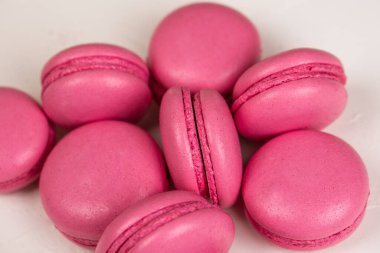 Makarnalar beyaz ahşap arka planda yakınlaşır. Tatlı ve renkli pembe Fransız badem kurabiyeleri. Evde yemek pişirmek.. 