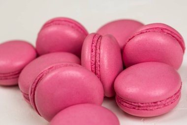 Makarnalar beyaz ahşap arka planda yakınlaşır. Tatlı ve renkli pembe Fransız badem kurabiyeleri. Evde yemek pişirmek.. 