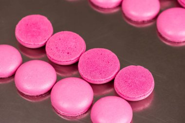 Makarnalar beyaz ahşap arka planda yakınlaşır. Tatlı ve renkli pembe Fransız badem kurabiyeleri. Evde yemek pişirmek.. 