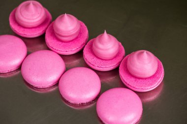 Makarnalar beyaz ahşap arka planda yakınlaşır. Tatlı ve renkli pembe Fransız badem kurabiyeleri. Evde yemek pişirmek.. 