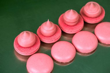 Makarnalar beyaz ahşap arka planda yakınlaşır. Tatlı ve renkli pembe Fransız badem kurabiyeleri. Evde yemek pişirmek.. 