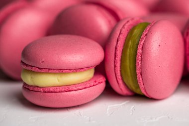 Makarnalar beyaz ahşap arka planda yakınlaşır. Tatlı ve renkli pembe Fransız badem kurabiyeleri. Evde yemek pişirmek.. 