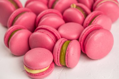 Makarnalar beyaz ahşap arka planda yakınlaşır. Tatlı ve renkli pembe Fransız badem kurabiyeleri. Evde yemek pişirmek.. 