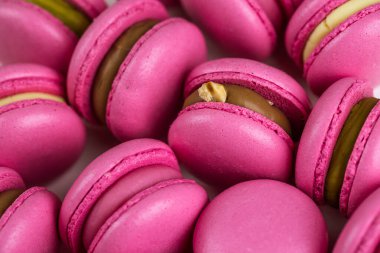 Makarnalar beyaz ahşap arka planda yakınlaşır. Tatlı ve renkli pembe Fransız badem kurabiyeleri. Evde yemek pişirmek.. 