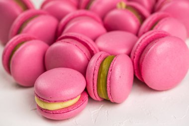 Makarnalar beyaz ahşap arka planda yakınlaşır. Tatlı ve renkli pembe Fransız badem kurabiyeleri. Evde yemek pişirmek.. 