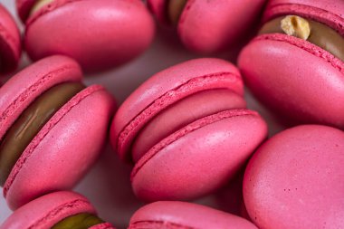 Makarnalar beyaz ahşap arka planda yakınlaşır. Tatlı ve renkli pembe Fransız badem kurabiyeleri. Evde yemek pişirmek.. 