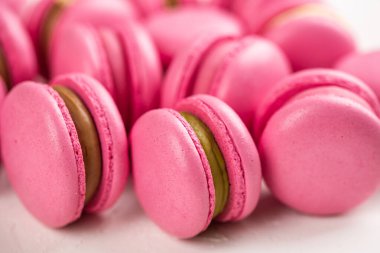 Makarnalar beyaz ahşap arka planda yakınlaşır. Tatlı ve renkli pembe Fransız badem kurabiyeleri. Evde yemek pişirmek.. 