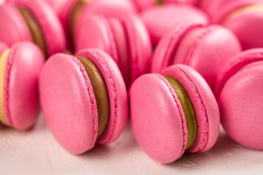 Makarnalar beyaz ahşap arka planda yakınlaşır. Tatlı ve renkli pembe Fransız badem kurabiyeleri. Evde yemek pişirmek.. 