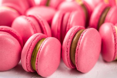 Makarnalar beyaz ahşap arka planda yakınlaşır. Tatlı ve renkli pembe Fransız badem kurabiyeleri. Evde yemek pişirmek.. 